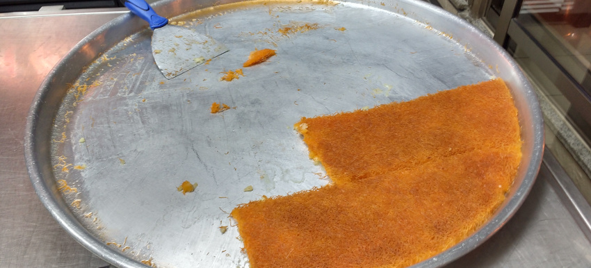 Arabische Süßspeise Knafeh: Ricotta-Mozzarella-Boden belegt mit zuckrigen Fäden.